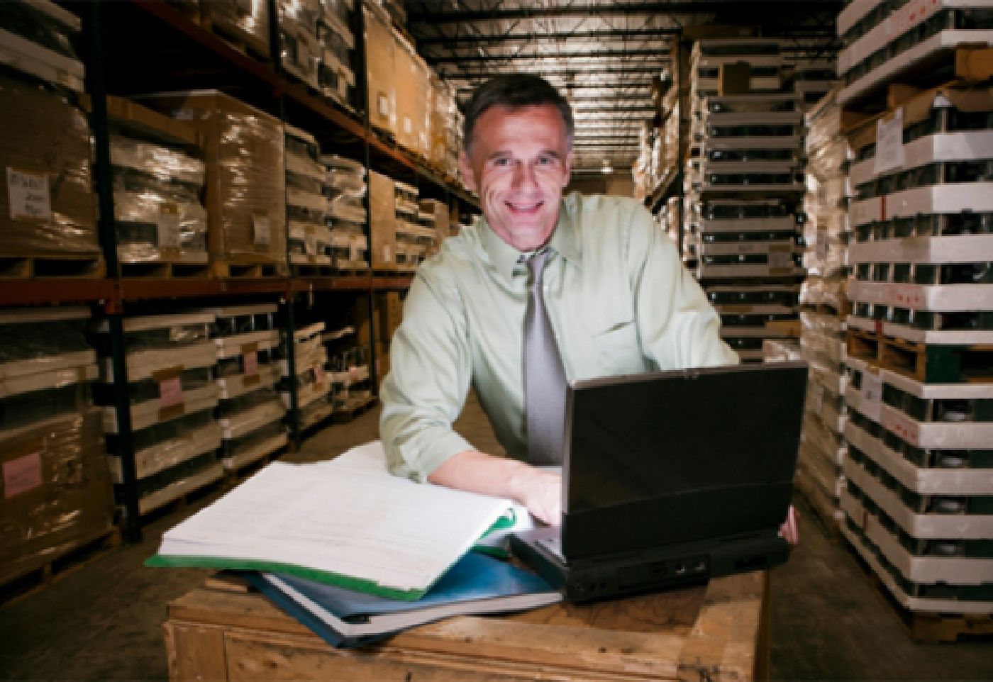 Man optimizing profits on spreadsheet in warehouse
